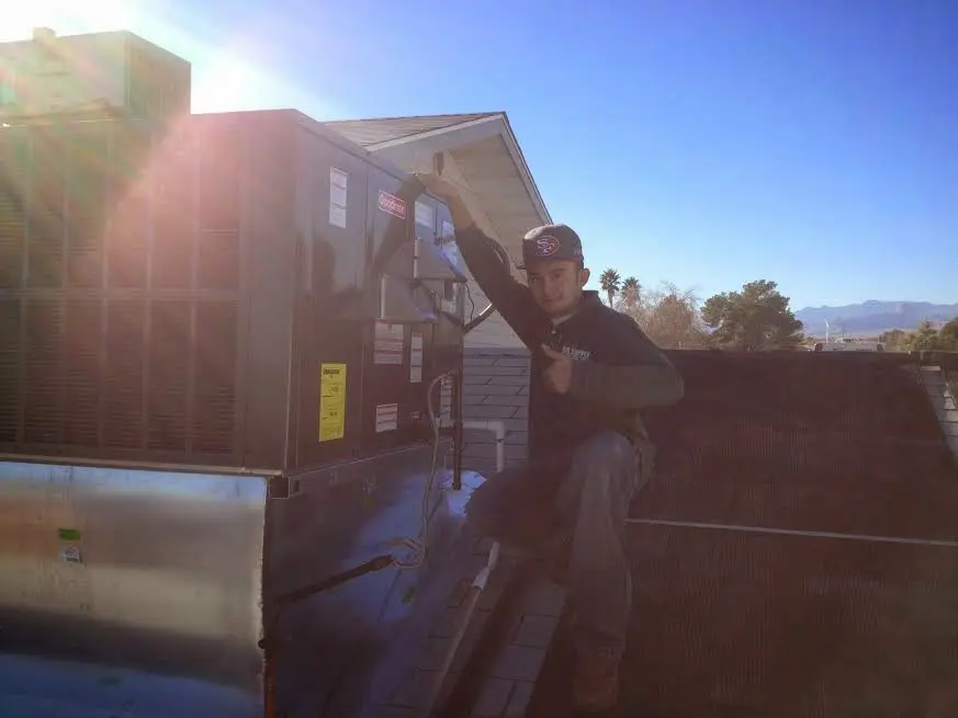 HVAC technician performing AC Tune-Up on a rooftop unit in Grand Blanc